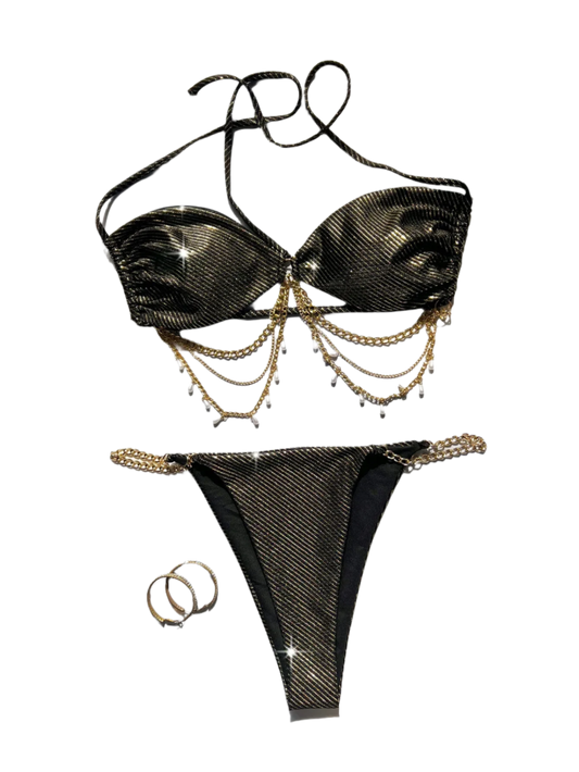 A glamorous black bikini with a metallic sheen, adorned with gold chain embellishments. The set includes a bandeau top and matching bottoms, offering a luxurious and stylish appearance.