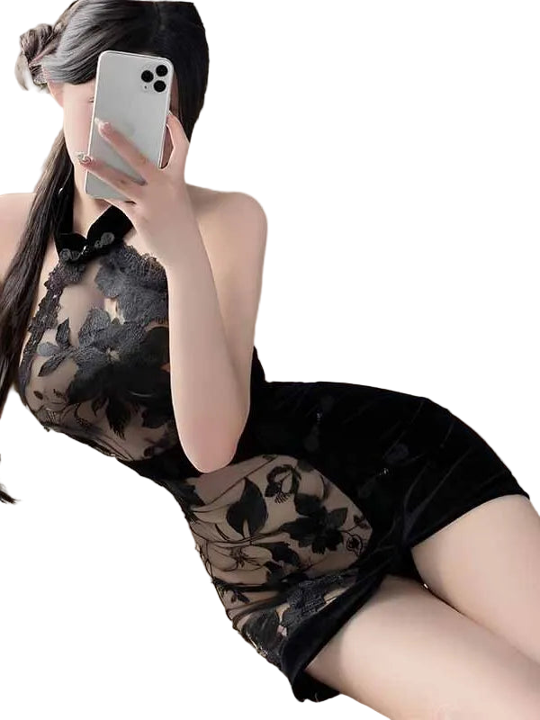 Person wearing a black lace dress holding a phone in a softly lit room.