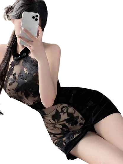 Person wearing a black lace dress holding a phone in a softly lit room.