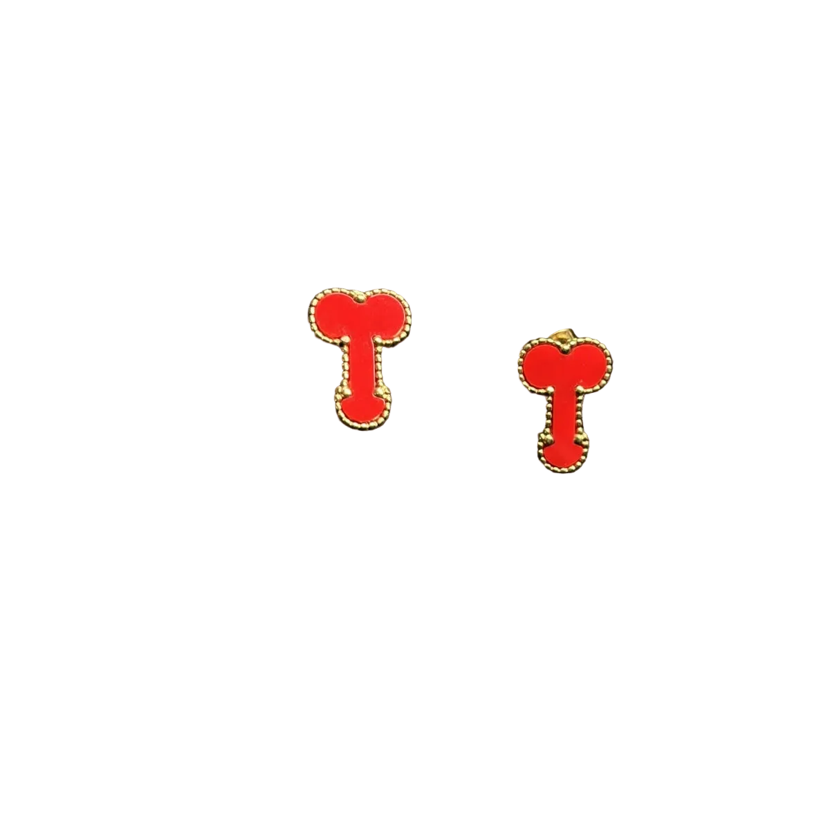 A pair of red enamel stud earrings shaped like stylized letters or symbols, outlined in gold-tone metal, displayed on a black textured surface next to a black foam block.
