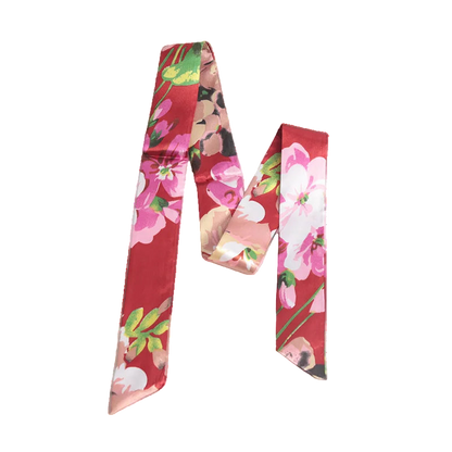 Two floral-patterned scarves on a white surface with a magazine underneath.