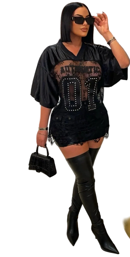 Woman in a stylish black outfit with studded details, standing in a room with a gold decorative mirror.