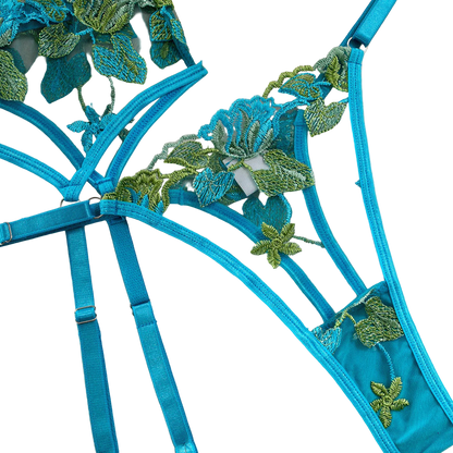 Blue lingerie set with green floral embroidery on a beige background