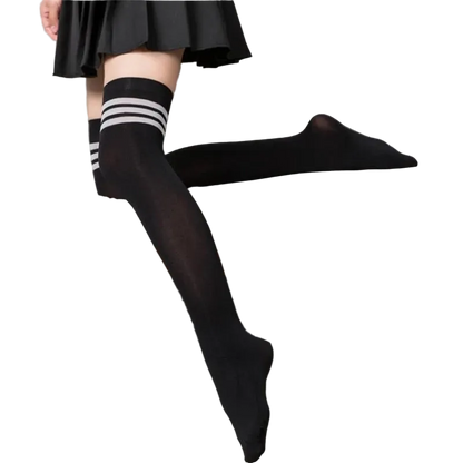 Person wearing black knee-high socks with white stripes sitting on a gray couch.