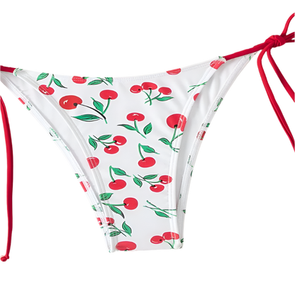 A white bikini with a cherry print. It features a classic triangle top and tie-side bottoms with red strings, giving it a playful and fruity look.
