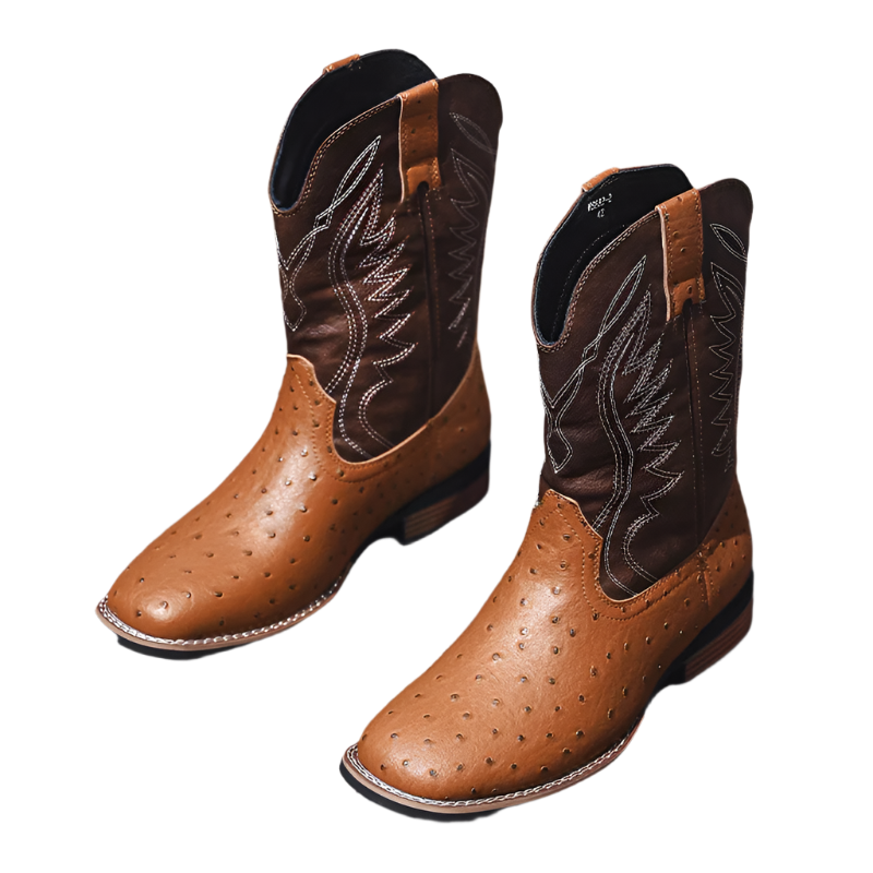 Pair of brown cowboy boots with black stitching on a wooden floor.