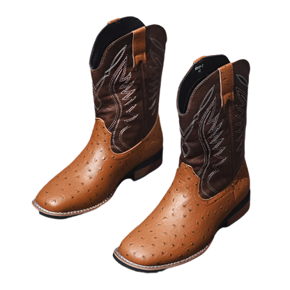Pair of brown cowboy boots with black stitching on a wooden floor.