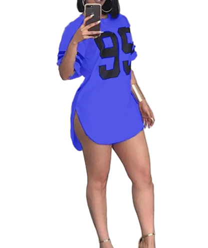 Person wearing a blue dress with '99' print, standing in a room.