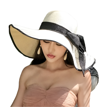 Woman wearing a large sun hat with a black ribbon against a leafy background