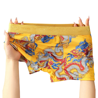 Yellow boxer briefs with dragon pattern held by a person on a white background
