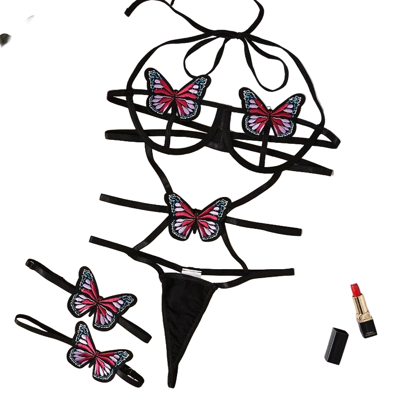 Black lingerie set with butterfly designs on a beige surface with flowers and a magazine.