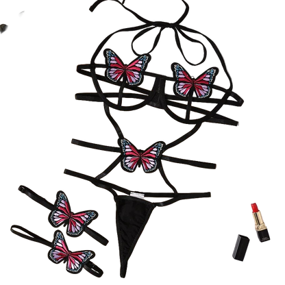 Black lingerie set with butterfly designs on a beige surface with flowers and a magazine.