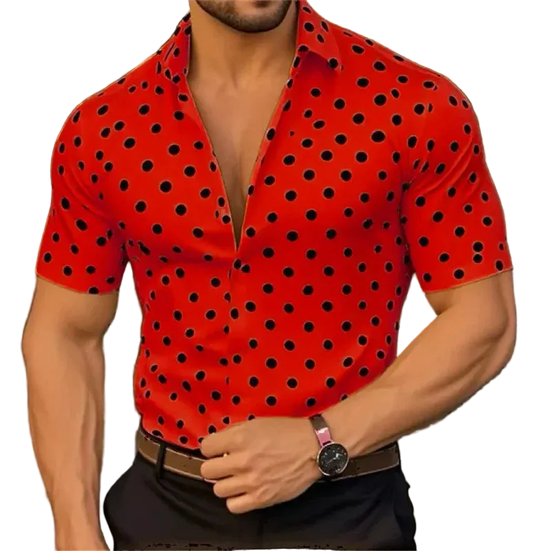 Man wearing a red shirt with black polka dots, standing against a blurred background