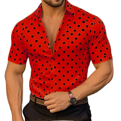 Man wearing a red shirt with black polka dots, standing against a blurred background