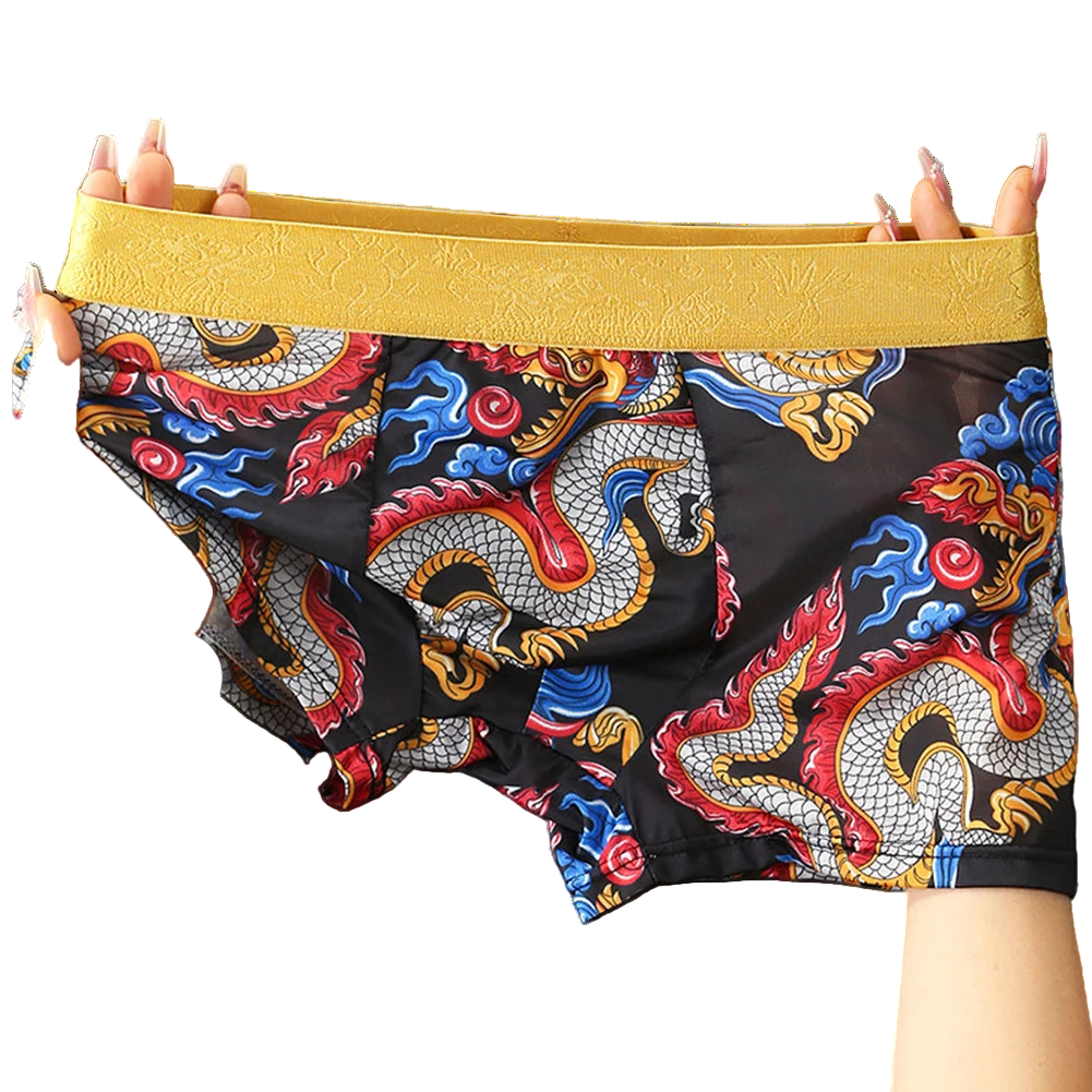 Colorful dragon-patterned boxer briefs with a yellow waistband held by hands against a gray background.