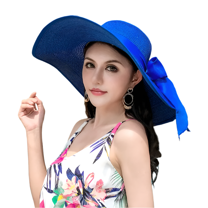 Woman wearing a large blue hat with a bow, sitting on a couch.