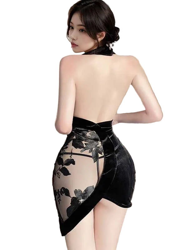 Woman wearing a black floral dress with sheer overlay in a room with curtains.