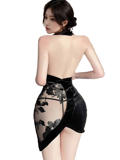 Woman wearing a black floral dress with sheer overlay in a room with curtains.