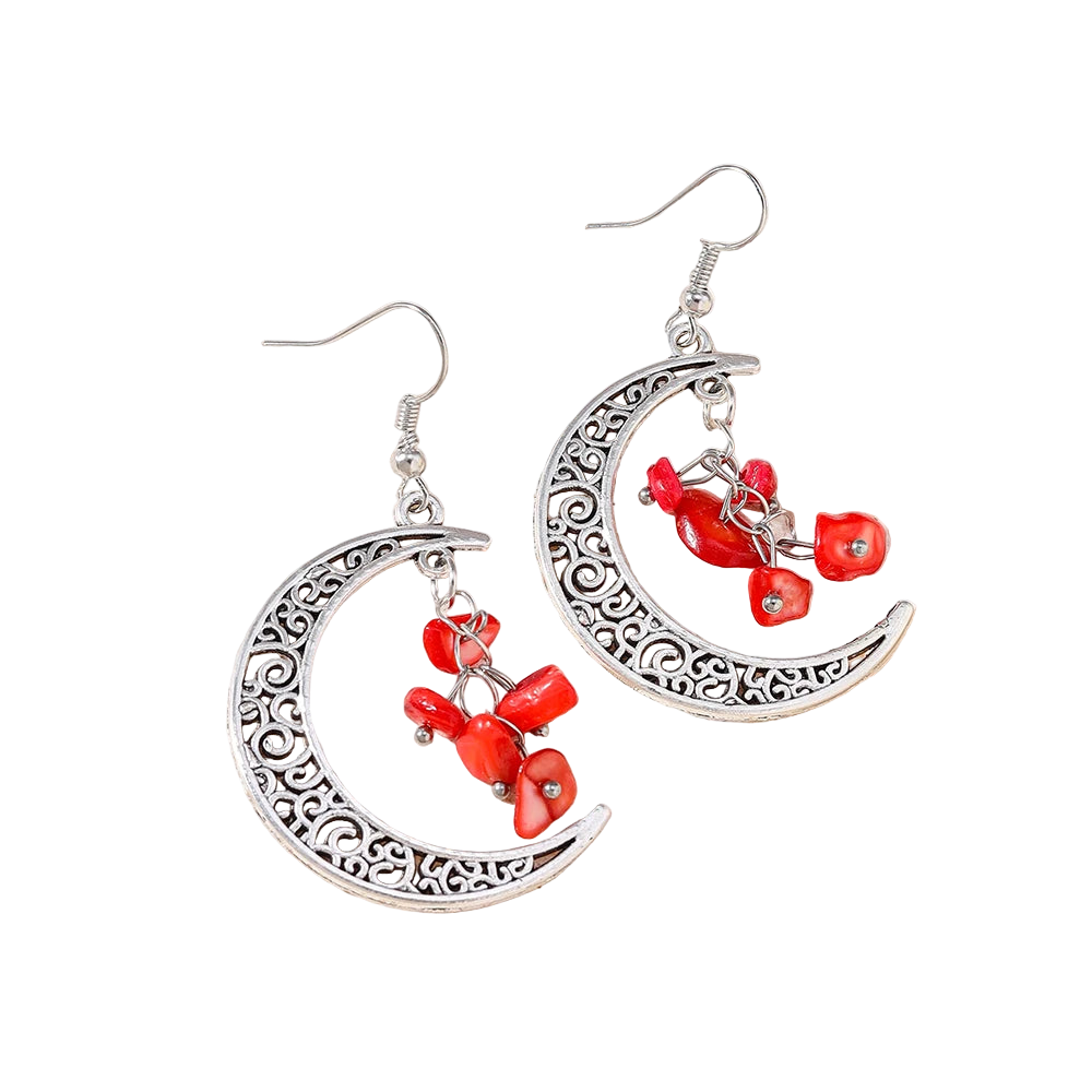 Silver earrings with red beads on a textured beige surface
