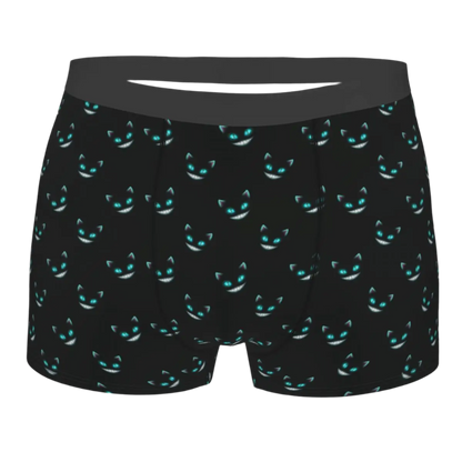 boxer shorts featuring the Cheshire Cat design from Alice in Wonderland, with glowing turquoise eyes and distinctive grinning teeth illuminated against a dark background.