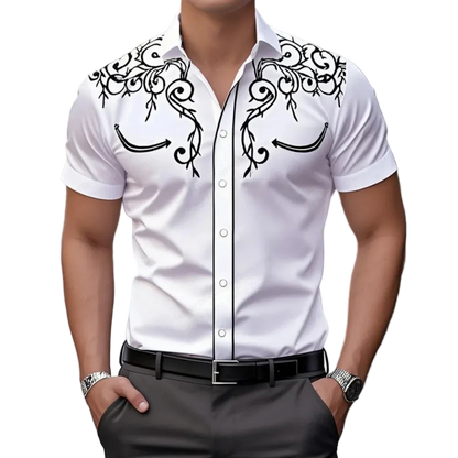 Man wearing a white shirt with black decorative patterns and dark pants.