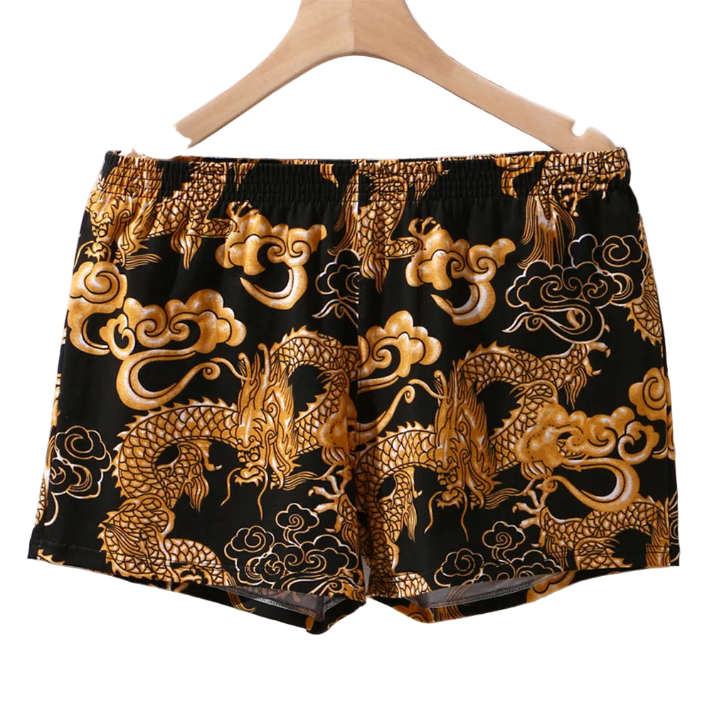 Black shorts with gold dragon and cloud patterns on a hanger.