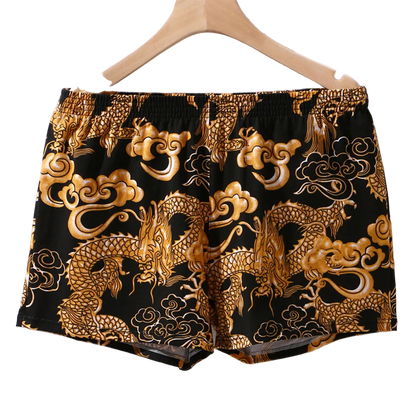 Black shorts with gold dragon and cloud patterns on a hanger.