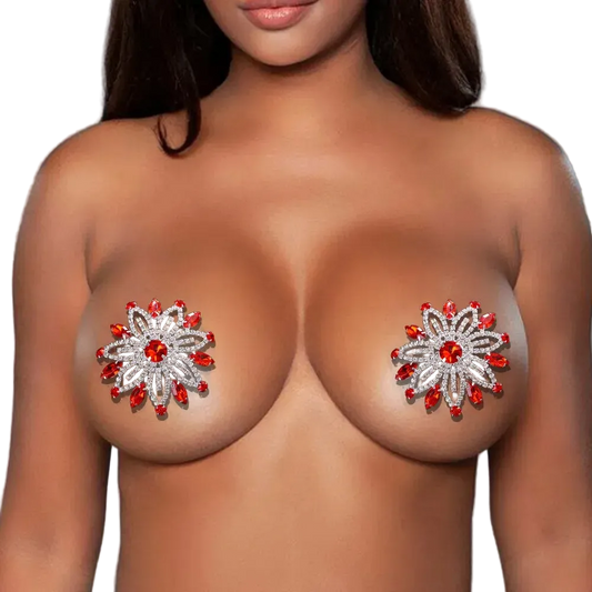 Woman wearing decorative breast pasties with floral designs and red stones on a gray background