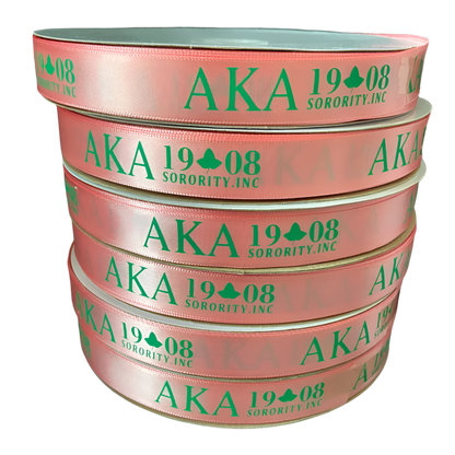 Stack of pink ribbons with green text 'AKA 1908 Sorority, Inc.' on a black background