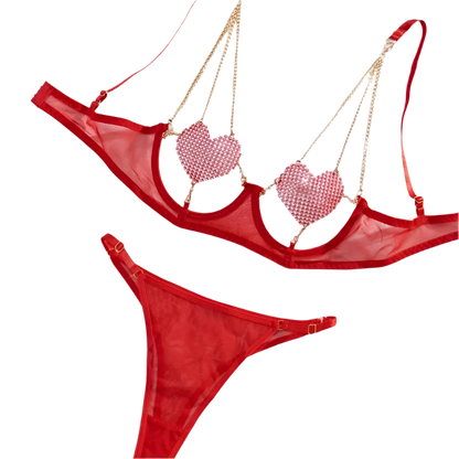 A red lingerie set with sparkling embellishments. The top features heart-shaped accents and is connected with gold chains, paired with a matching bottom.