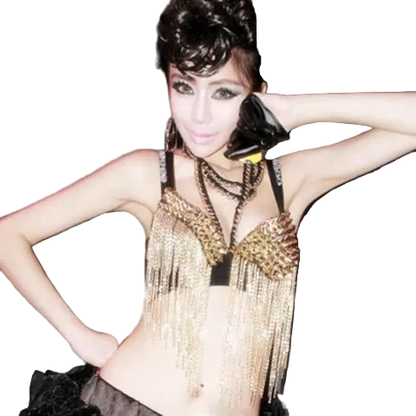 A woman modeling a black and gold fringed belly dance costume top with matching layered necklaces, posing against a dark gray background.