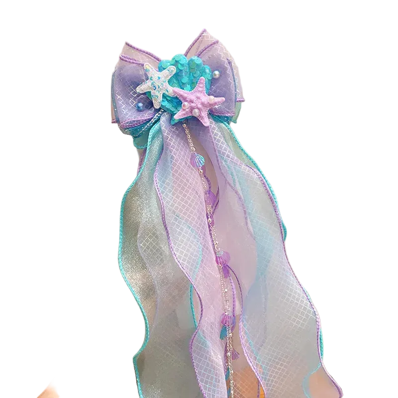 Decorative bow with starfish and ribbons held against a neutral background