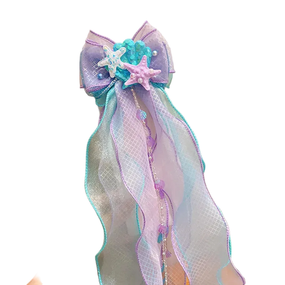 Decorative bow with starfish and ribbons held against a neutral background