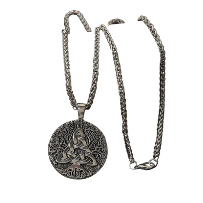 A silver Celtic knot pendant necklace with a triquetra design, displayed on a dark rock against a black reflective surface.