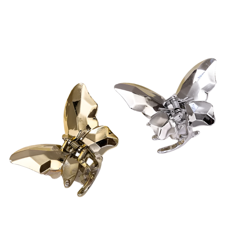 Gold and silver butterfly-shaped hair clips on a white fabric background