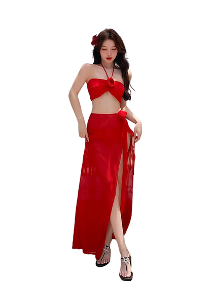 Woman in a red outfit standing on a beach with ocean view and hanging lanterns.