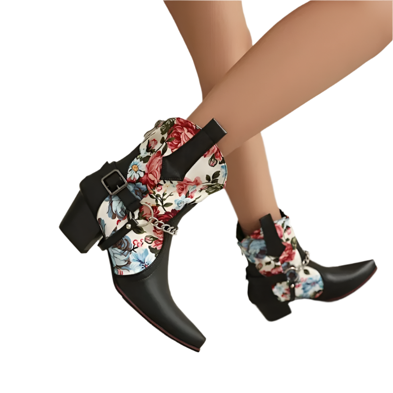 Black pointed-toe boots with floral pattern and buckles on a neutral background