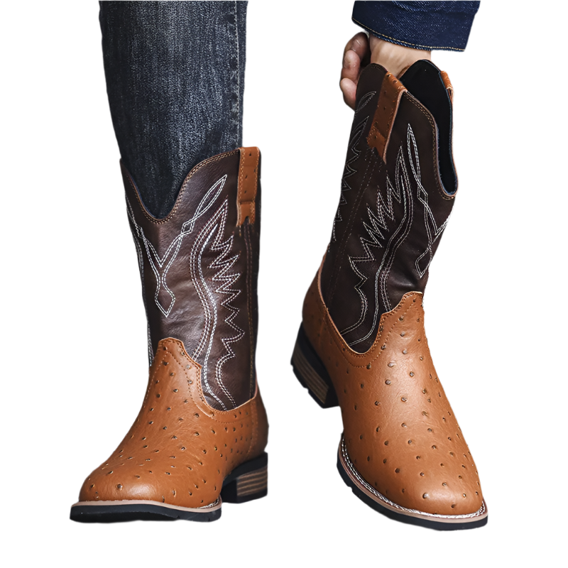 Brown cowboy boots with detailed stitching worn by a person on a gray surface.