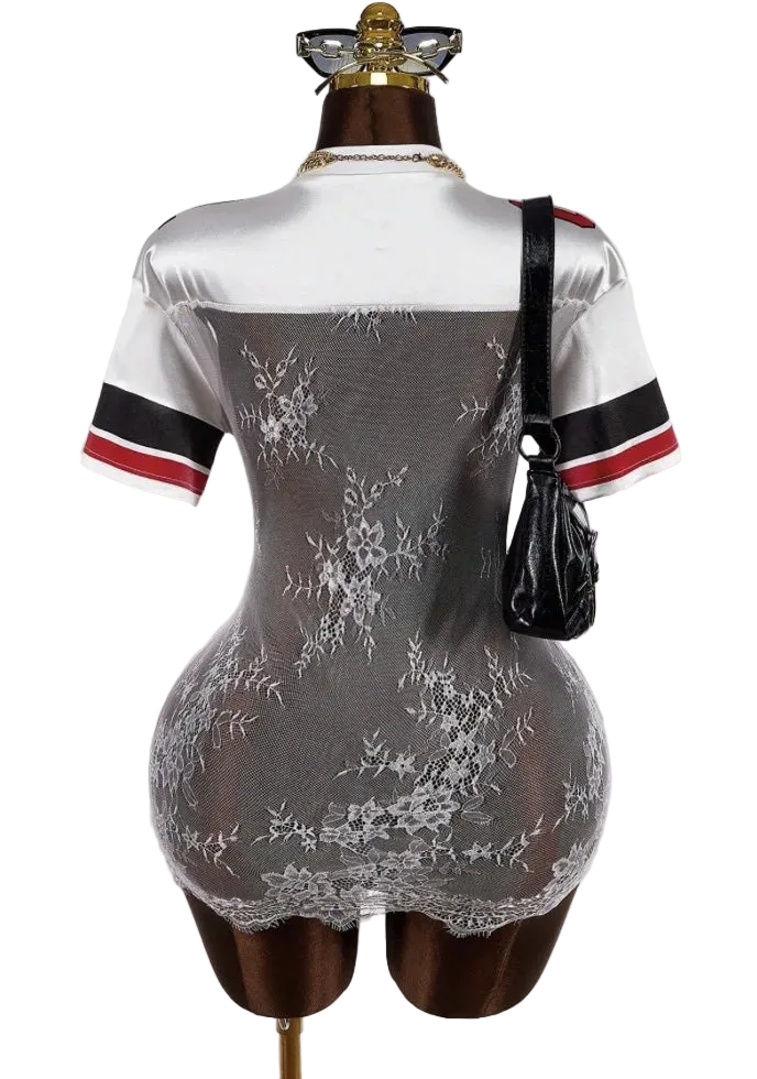 Mannequin wearing a white lace dress with black and red accents on a plain background
