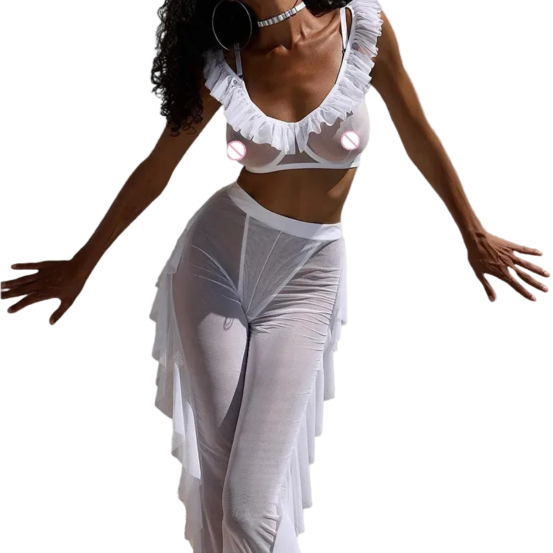 A model wearing a white sheer ruffled lingerie set consisting of a ruffled crop top and matching high-waisted sheer maxi skirt, posed against a solid light gray background.