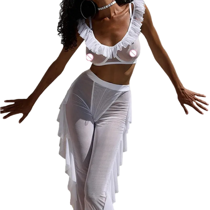 A model wearing a white sheer ruffled lingerie set consisting of a ruffled crop top and matching high-waisted sheer maxi skirt, posed against a solid light gray background.