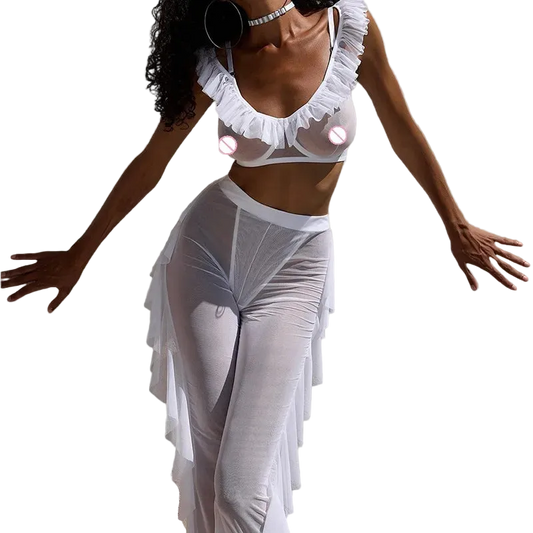 A model wearing a white sheer ruffled lingerie set consisting of a ruffled crop top and matching high-waisted sheer maxi skirt, posed against a solid light gray background.