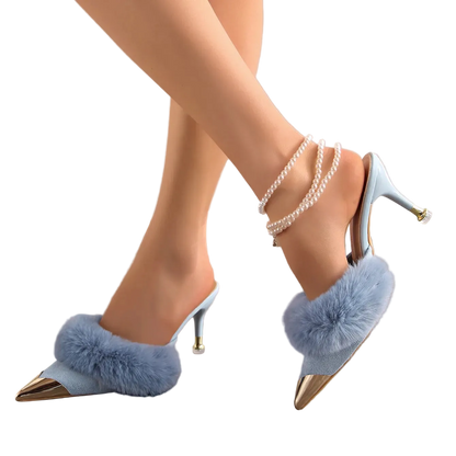 Blue high-heeled shoes with fluffy pom-poms worn by a person on a neutral background