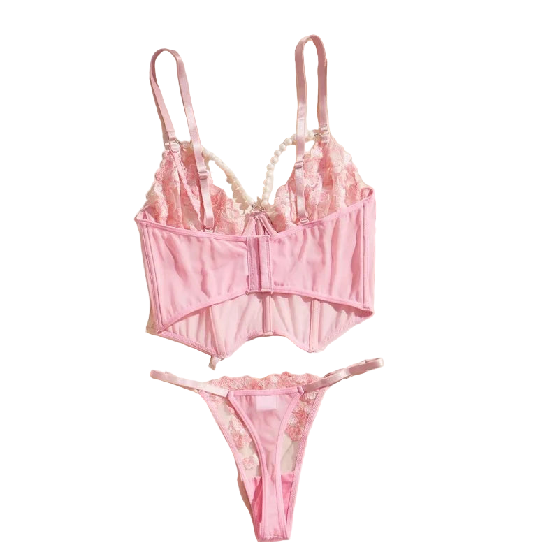Pink lingerie set on a white surface with a beige jacket and decorative items.