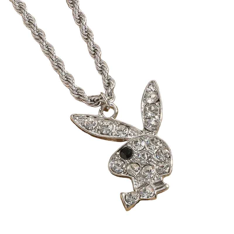 A silver-tone bunny pendant necklace paved with clear rhinestones, featuring a small black eye detail, hanging from a thick silver rope chain on a textured tan background.