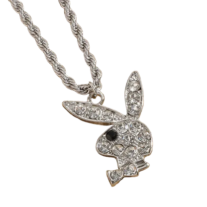 A silver-tone bunny pendant necklace paved with clear rhinestones, featuring a small black eye detail, hanging from a thick silver rope chain on a textured tan background.