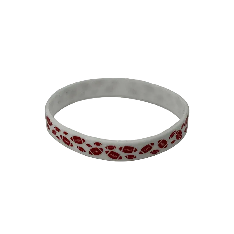 A white silicone wristband featuring a repeating pattern of red footballs with white 'NFL' logos, photographed on a neutral gray background.