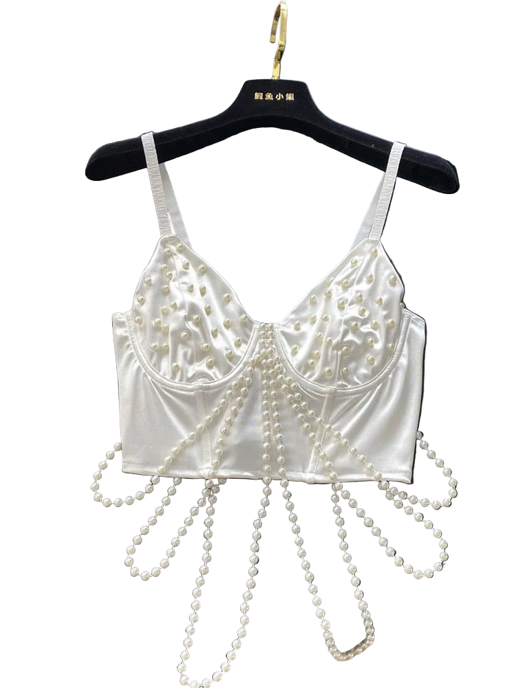 White lace bralette with pearl embellishments on a black surface