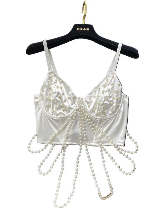 White lace bralette with pearl embellishments on a black surface