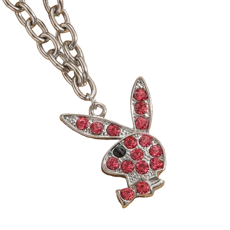 A silver-tone bunny pendant necklace embellished with red rhinestones, resting on a textured beige fabric background.